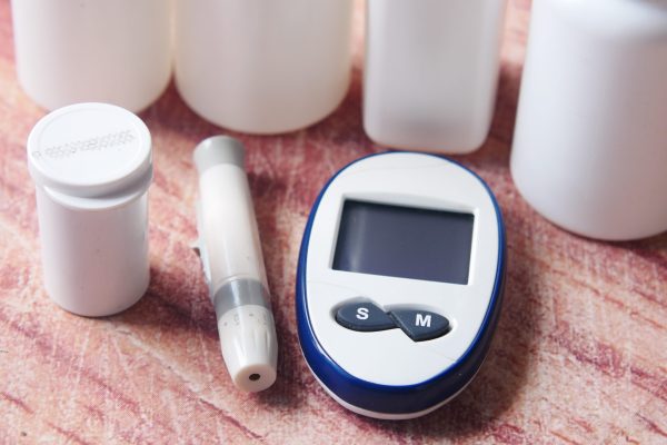 Close up of diabetic measurement tools and pills on pink background .